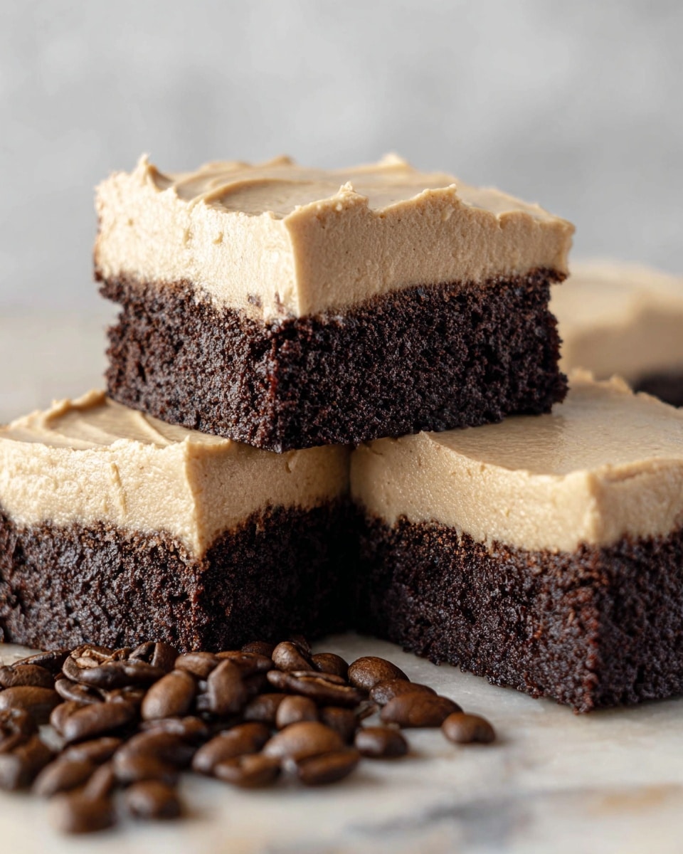 The image shows three brownie squares with thick, creamy light brown frosting on top of dark, rich chocolate brownie bases. The brownies have a rough, crumbly texture, while the frosting is smooth and slightly uneven. One brownie square is stacked on top of the other two, which are side by side. In front of the brownies, there are scattered dark brown coffee beans adding a rustic feel. The background is a soft white marbled texture that contrasts with the deep brown and light frosting colors, making the brownies stand out. photo taken with an iphone --ar 4:5 --v 7