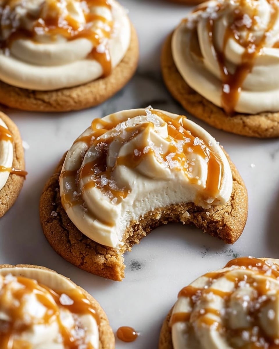 The image shows a close-up of soft cookies on a white marbled surface, each topped with a thick layer of white cream. Over the cream, there are smooth, glossy caramel drizzle lines running across, sprinkled with coarse salt crystals. The cookie in the center has a bite taken out of it, revealing a light brown, slightly crumbly texture inside with a darker, baked bottom layer. Other cookies are positioned around it, slightly blurred to keep focus on the bitten cookie. photo taken with an iphone --ar 4:5 --v 7