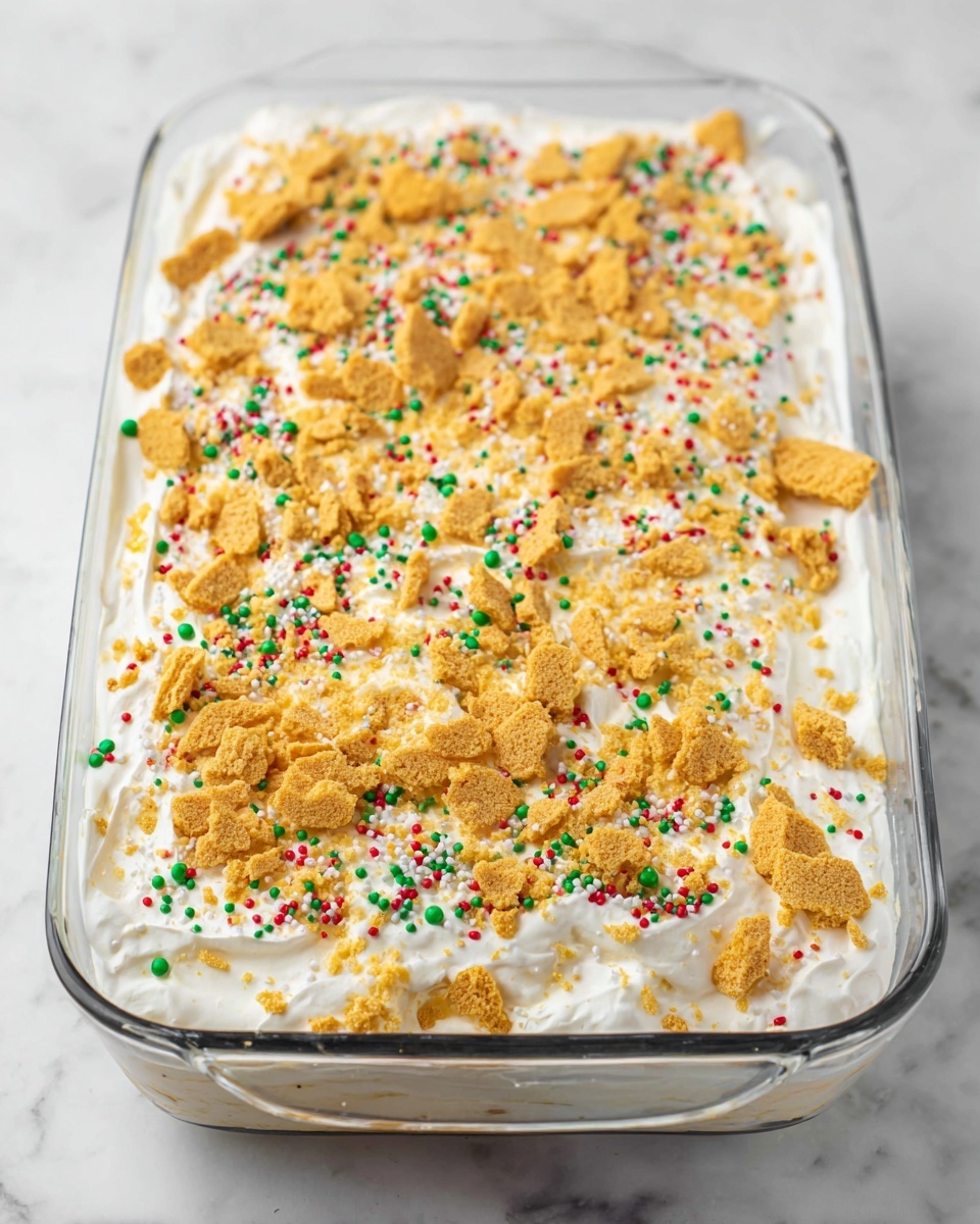 The image shows a single square piece of a layered dessert on a white plate placed on a white marbled surface. The dessert has three visible layers: the bottom layer is a light brown crumbly crust, the middle layer is thick and white with colorful sprinkles mixed in, and the top layer is a creamy white layer sprinkled with more colorful sprinkles and small crumbs. In the background, there is a glass of milk slightly out of focus. The overall setting is bright and clean. Photo taken with an iphone --ar 4:5 --v 7