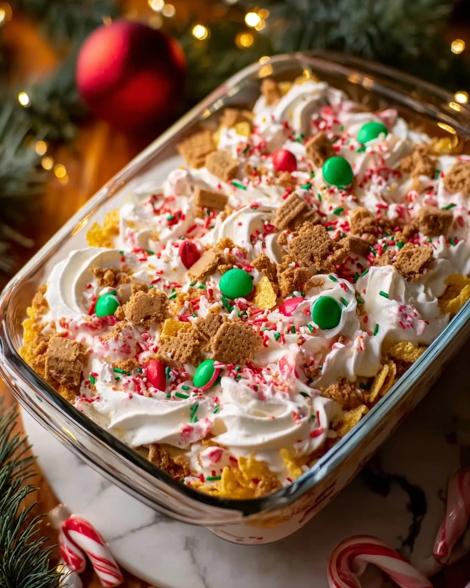 A rectangular glass dish filled with a layered dessert where the top layer is full of white whipped cream swirled into soft peaks, sprinkled with colorful red, green, and pink round and sprinkle-shaped candy pieces. Crushed light brown cookies are scattered on top, along with small broken pieces of candy canes that have red and white stripes, and light yellow star-shaped cereal flakes spread evenly across the surface. The dish is placed on a white marbled texture with warm holiday lights and green pine branches in the background. Photo taken with an iphone --ar 4:5 --v 7