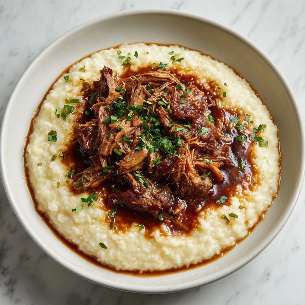 The dish is served on a white bowl placed on a white marbled surface. The base layer consists of creamy, light beige risotto spread evenly in a round shape. On top of the risotto, there is a hearty portion of shredded brown meat covered in a thick, rich dark brown sauce. Small pieces of green herbs are sprinkled over the meat and around the edges of the risotto, adding a fresh contrast in color. The textures show the softness of the risotto and the tender, juicy strands of meat mixed with the smooth sauce. Photo taken with an iphone --ar 4:5 --v 7