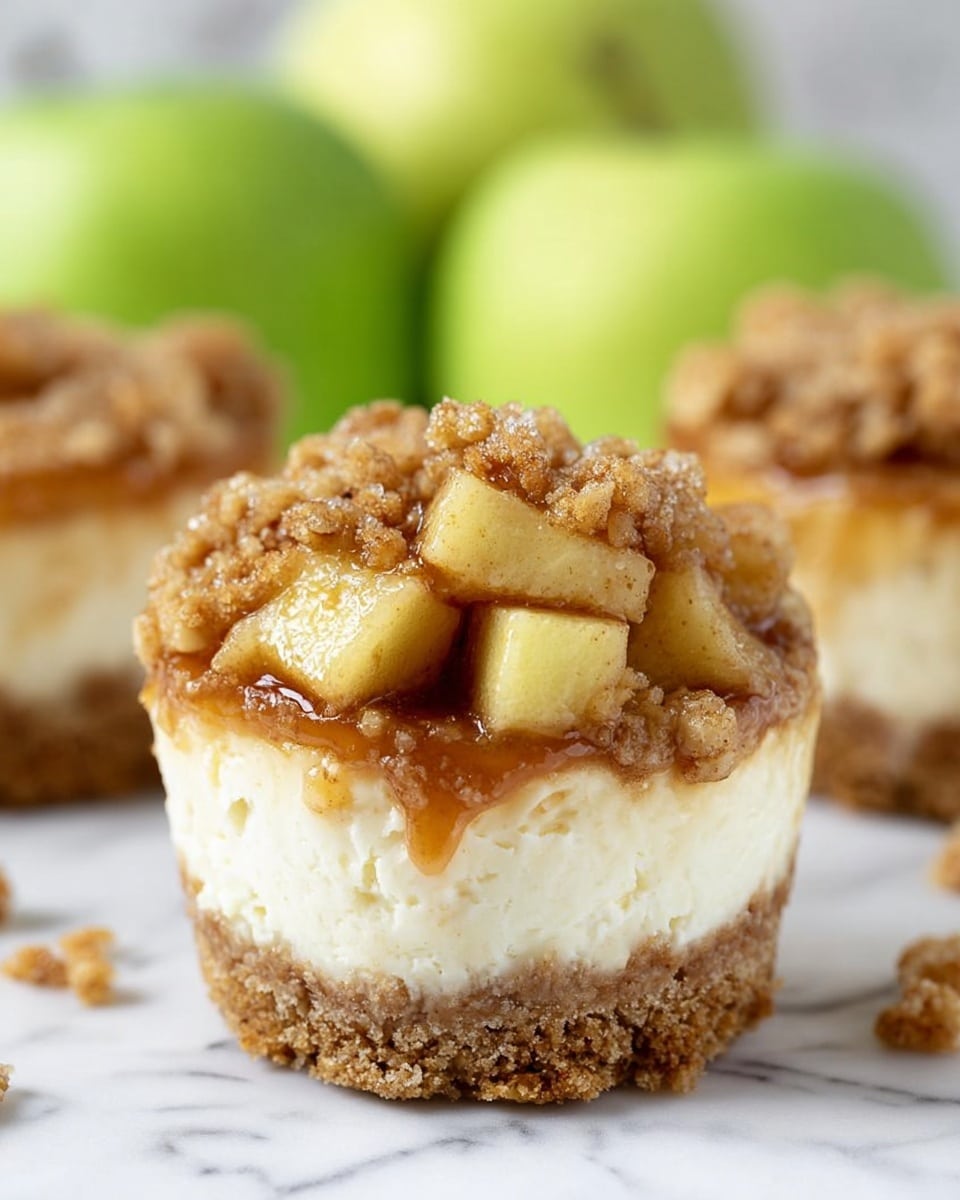 The image shows mini cheesecakes with four clear layers arranged on a white plate over a white marbled surface. The bottom layer is a crumbly, dark golden-brown crust with a slightly rough texture. Above that is a smooth, creamy pale yellow cheesecake layer with fine vertical ridges on the side. On top of the cheesecake is a thick, uneven layer of crumbly, light brown streusel with a coarse texture. The top layer is a generous swirl of white whipped cream drizzled with shiny caramel sauce that runs down the sides and onto the plate. There are small crumbs and drops of caramel scattered around the plate. Photo taken with an iphone --ar 4:5 --v 7