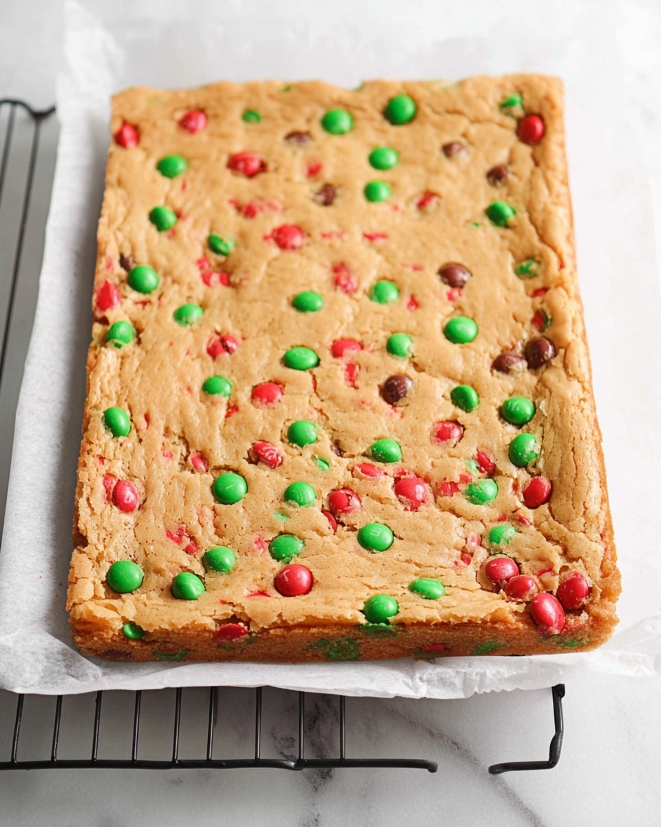 A stack of four square blondie bars sits on a white plate, each bar showing a light golden-brown top with a slightly cracked texture. Bright red and green candy-coated chocolate pieces are embedded evenly on the surface and visible inside the bars, adding pops of color within the soft, dense layers. The bars rest on a wooden board against a white marbled background with a soft-focus white cloth featuring small red and green dots in the background. Photo taken with an iphone --ar 4:5 --v 7
