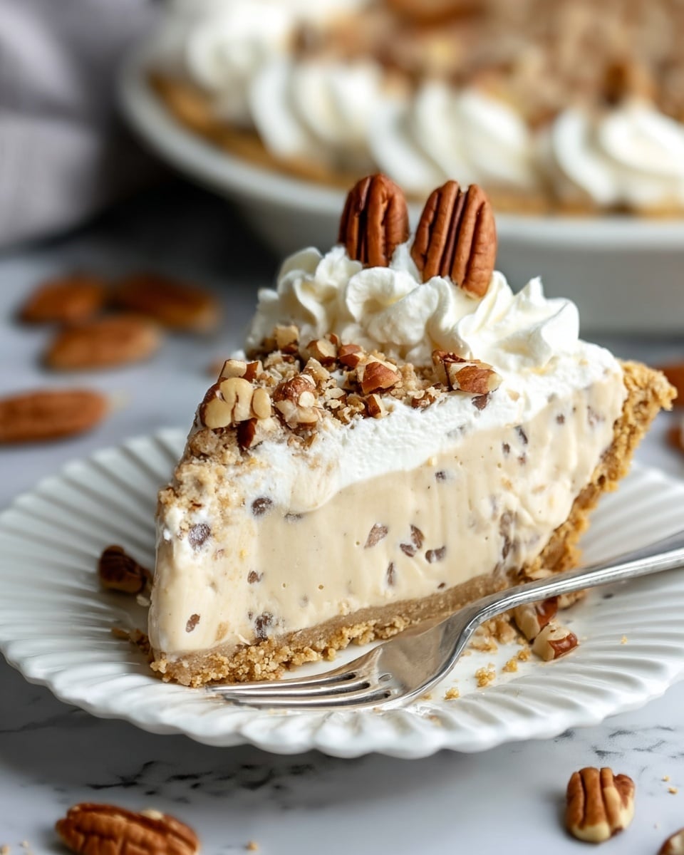 A slice of pie on a white fluted plate shows three main layers: a crumbly light brown crust at the bottom, a thick creamy beige filling with small dark nut pieces spread evenly throughout in the middle, and a fluffy white whipped cream layer on top, covered with chopped pecans and a swirl of whipped cream crowned by two whole pecans, a silver fork sits beside the slice, all placed on a white marbled surface with pecans scattered around and a pie dish filled with more pie blurred in the background, photo taken with an iphone --ar 4:5 --v 7