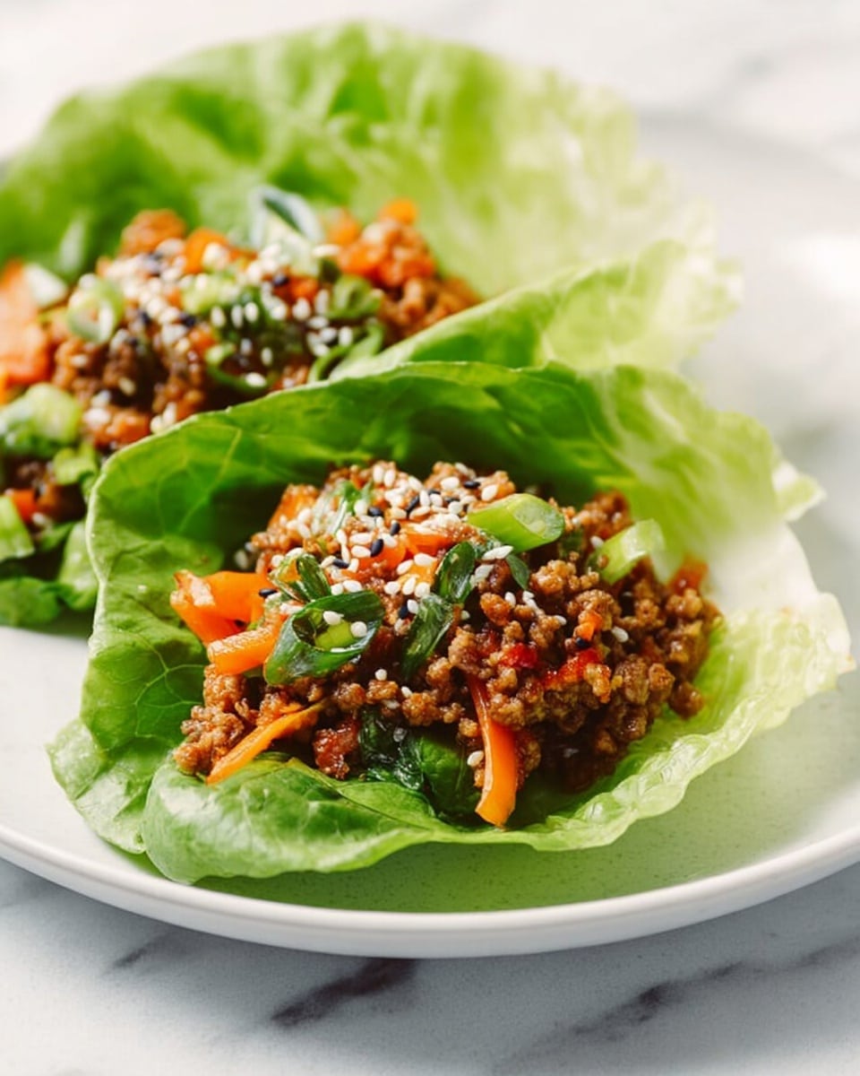 The image shows two lettuce cups on a white plate, each cup lined with bright green, soft lettuce leaves forming the base layer. Inside, the filling is made of finely chopped cooked meat mixed with small diced orange and green vegetables, creating a colorful, textured middle layer. The meat mixture is topped with a sprinkle of white and black sesame seeds, adding contrast and a bit of texture. The plate sits on a white marbled surface, bright and clean, highlighting the fresh colors of the dish. Photo taken with an iphone --ar 4:5 --v 7