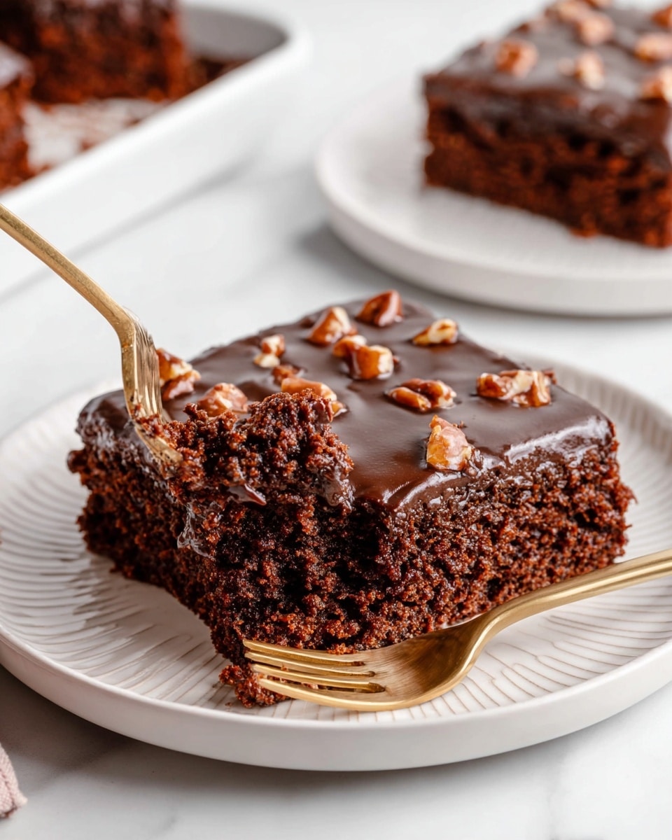 A square piece of chocolate cake with a thick dark brown chocolate frosting layer on top, studded with chunks of nuts spread evenly. The cake layer beneath is dense and moist, showing a rich brown color with a slightly crumbly texture. A gold fork is lifting a small bite from the cake’s bottom left corner. The cake sits on a white plate with subtle ridges on the edge, all placed on a white marbled surface. In the background, part of another white plate with a similar cake piece and gold fork is visible. Photo taken with an iphone --ar 4:5 --v 7